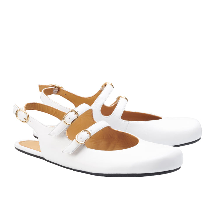 Wir präsentieren den ZAQQ QOMET White: ein Paar weiße Flats im stylischen Design mit drei Riemen mit Goldschnallen und offener Rückseite, perfekt für alle, die den eleganten Barfuß-Stil zu schätzen wissen.