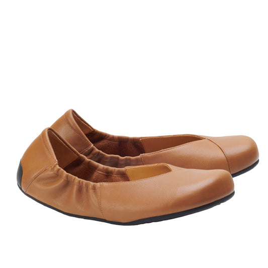 Ein Paar braune ZAQQ MAIQA Ballerinas mit elastischen Seiten und abgerundeten Zehen, von der Seite präsentiert. Die Schuhe haben eine glatte Textur und schwarze Sohlen, die eine flexible Sohle bieten, die ideal für Komfort und lässiges Tragen ist.