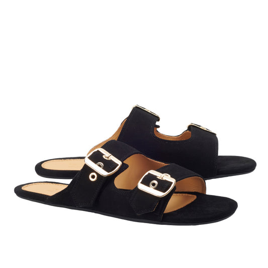 Die ZAQQ UQO Black Sandalen zeigen ein schlichtes, elegantes Design mit zwei großen goldenen Schnallen an Velourslederriemen. Diese schwarzen Slide-Sandalen zeichnen sich durch eine ultradünne Sohle aus und werden vor einem strahlend weißen Hintergrund präsentiert.