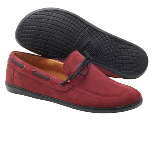 Die Loafer QEA Velours Bordeaux von ZAQQ sind aus bordeauxfarbenem Veloursleder mit schwarzen Gummisohlen gefertigt. Ein Schuh ist so angewinkelt, dass die Seite und die Oberseite sichtbar sind, wobei eine Schleife auf dem Vorderblatt hervorgehoben wird, während der andere Schuh so positioniert ist, dass die strukturierte Sohle sichtbar ist.