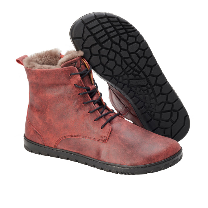 Die QUINTIC Winter Velours Red Stiefel von ZAQQ bieten mit ihrem roten Lederdesign und der schwarzen Sohle eine verbesserte Rutschfestigkeit. Sie verfügen über schwarze Schnürsenkel und ein weiches, flauschiges Innenfutter und werden so präsentiert, dass ein Stiefel aufrecht steht, während der andere die strukturierte Sohle freigibt.