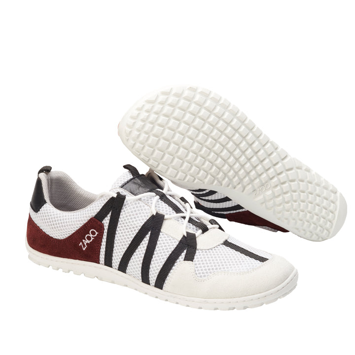 Wir präsentieren die RIQ White Red Sneaker von ZAQQ: Diese stylischen Schuhe haben eine weiße Basis mit schwarzen Streifen und kastanienbraunen Akzenten. Einer steht aufrecht, der andere ist so positioniert, dass seine strukturierte Sohle hervorgehoben wird. Sie wurden mit Blick auf optimale Atmungsaktivität entworfen, sind aus atmungsaktivem Mesh-Material gefertigt und haben ein Schnürdesign.