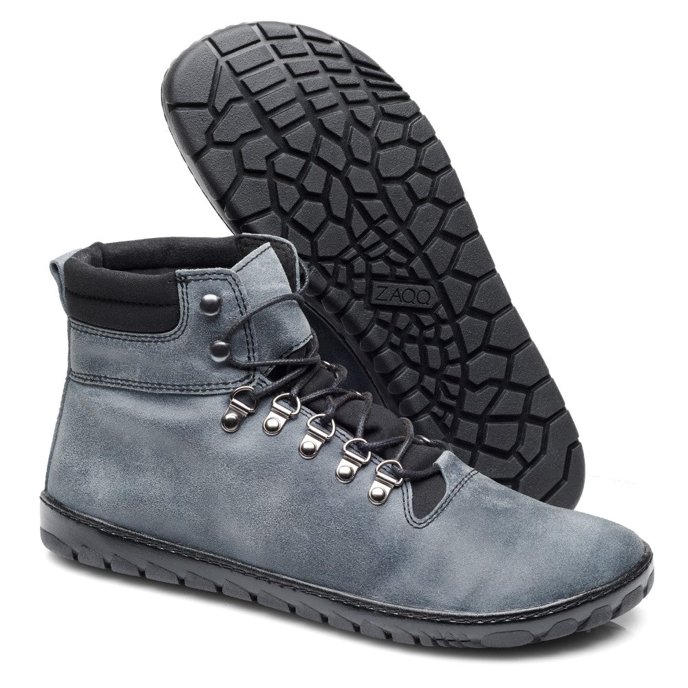 Die EXPEQ Lunar Waterproof-Stiefel von ZAQQ, graue High-Tops mit schwarzen Schnürsenkeln und einer abriebfesten Kautschuksohle, sprechen Ihren Abenteuergeist an. Metallösen sorgen für einen robusten Touch, wobei ein Stiefel aufrecht steht und der andere geneigt ist, um sein strukturiertes Design zu präsentieren, perfekt für jedes Outdoorabenteuer.