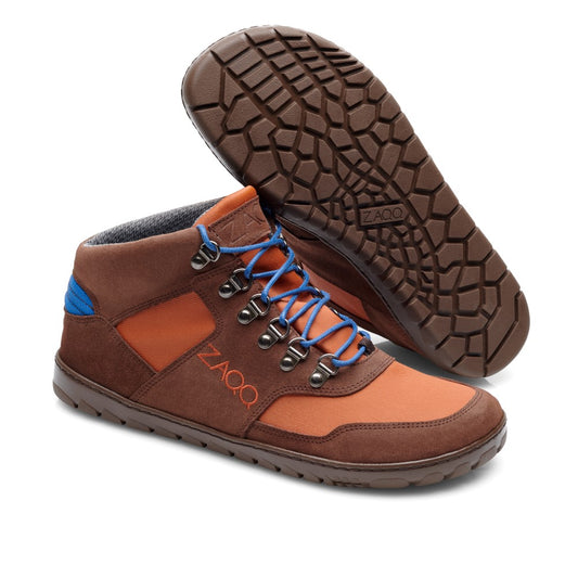 Die HIQE Mid Terracotta Waterproof Wanderschuhe von ZAQQ bestehen aus einer Mischung aus Wildleder und Stoff in Braun und Orange, ergänzt durch blaue Schnürsenkel. Sie sind im Barfußschuh-Stil gestaltet und verfügen über eine strukturierte Outdoorsohle für besseren Halt, wobei der Markenname ZAQQ prominent an der Seite angebracht ist.