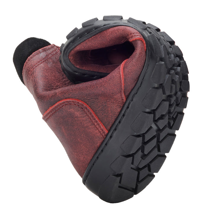 Der PARQER Red von ZAQQ ist ein roter Lederstiefel, der in der Mitte gefaltet ist, um seine Flexibilität hervorzuheben, und über eine strapazierfähige schwarze ZAQQ Outdoorsohle mit tiefen Profilen für optimalen Halt verfügt. Die sichtbaren Nähte und die abgenutzte Textur verleihen diesem Premium-Schuhwerk aus Nappaleder einen rustikalen, abgenutzten Look.