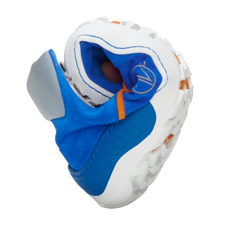 Nahaufnahme des ultraflexiblen, futuristischen, in der Mitte gebogenen TERRAQ Azure Waterproof-Sneakers. Der ZAQQ-Schuh verfügt über eine weiße, klobige Sohle mit orangefarbenen Akzenten, ergänzt durch ein blaues Obermaterial mit glattem Veloursleder in grauen und orangefarbenen Details und trägt deutlich sichtbar „ZAQQ“ auf der Seite.