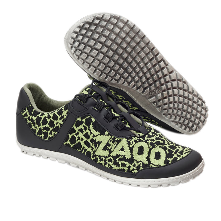 Sportliche Sneaker in schwarz-neongrünem Musterdesign mit seitlichem „ZAQQ“-Logo. Sie tragen den Namen QINGSTON Green, sind aus veganen Materialien gefertigt und haben schwarze Schnürsenkel und eine strukturierte Sohle für mehr Grip auf weißem Hintergrund.