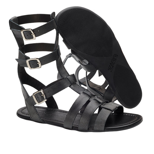 Die Gladiator-Sandalen QORA Black Silver von ZAQQ verfügen über mehrere Riemen und Schnallenverschlüsse. Eine Sandale steht aufrecht und hebt ihre eleganten Seiten- und Knöchelriemen hervor, während die andere mit der Sohle nach oben liegt und das detaillierte Profildesign zur Schau stellt. Ideal für einen extravaganten Modestil.