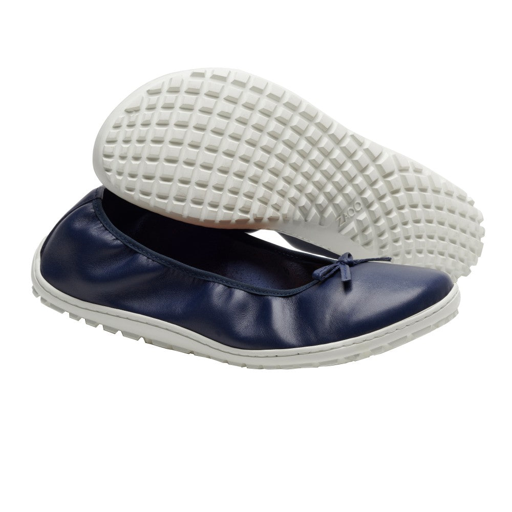 Die SUQAR Darkblue Schuhe von ZAQQ sind ein Paar marineblaue Slipper aus Glanzleder mit einer weißen strukturierten Sneakersohle und einer kleinen Schleife auf der Vorderseite. Ein Schuh steht aufrecht, während der andere auf der Seite liegt und strahlt sowohl Eleganz als auch Komfort aus.