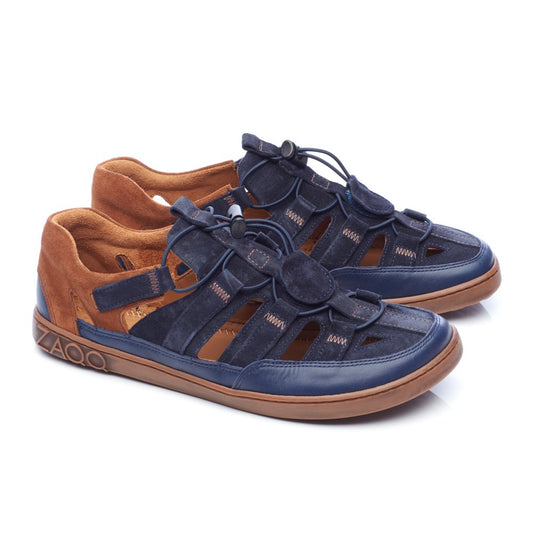 Das Produkt QERRY Blue Cognac von ZAQQ ist ein Paar stylische Sandalen mit dunkelblauen Riemen und Akzenten aus braunem Veloursleder. Sie haben verstellbare Schnürsenkel und eine hellbraune Sohle, abgerundet durch die Marke ZAQQ an der Seite. Diese modernen Barfußschuhe bieten ein lässiges Design, das ideal für das zeitgenössische Leben ist.