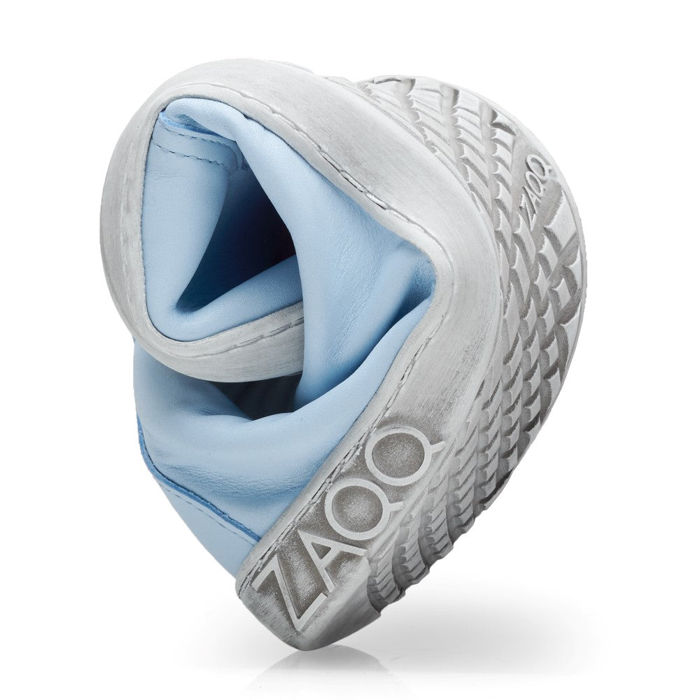 Der TAQQ Nappa Lightblue von ZAQQ verfügt über eine einzigartige und flexible Sohle, die kreativ in eine kreisförmige Form gedreht ist, um ihre Weichheit und Biegsamkeit hervorzuheben. Der Schuh trägt das Markenlogo an der Seite.